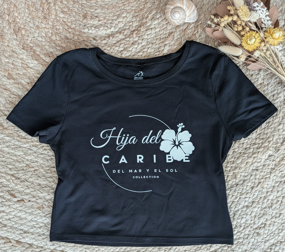Black t-shirt with 'Hija del Caribe' design on a textured surface with decorative elements.
