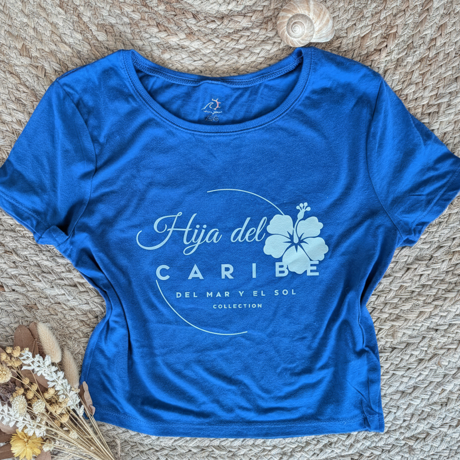 Blue t-shirt with 'Hija del Caribe' text and flower design on a textured surface.