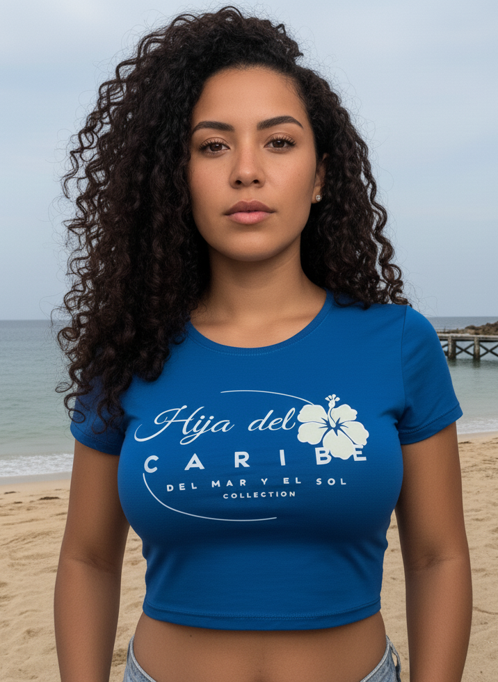 Woman wearing a blue t-shirt with a floral design and text Hija del Caribe Del Mar y el Sol Collection on a beach