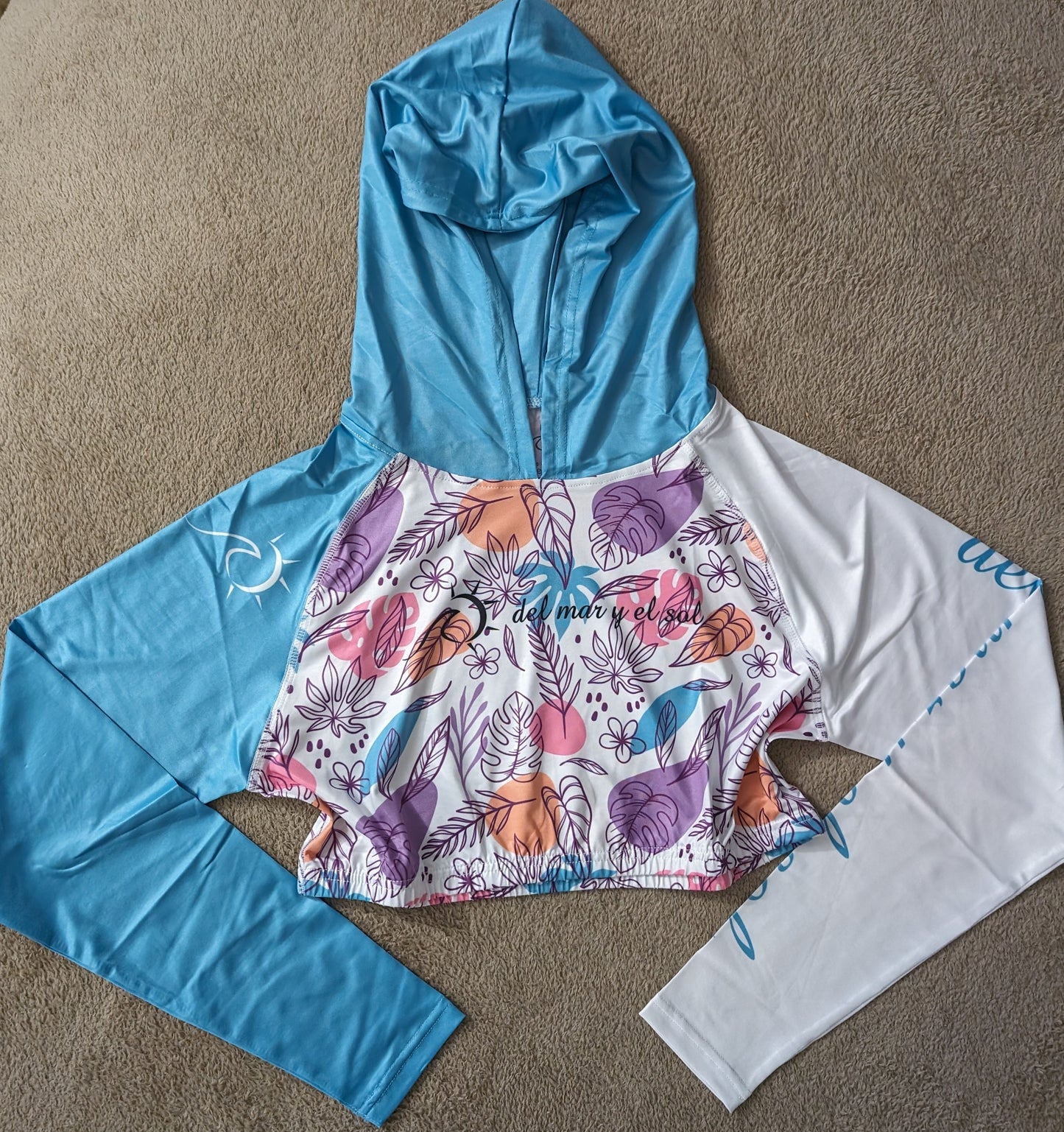 Tropical floral cropped rash guard with blue and white sleeves and a colorful floral pattern on the front.