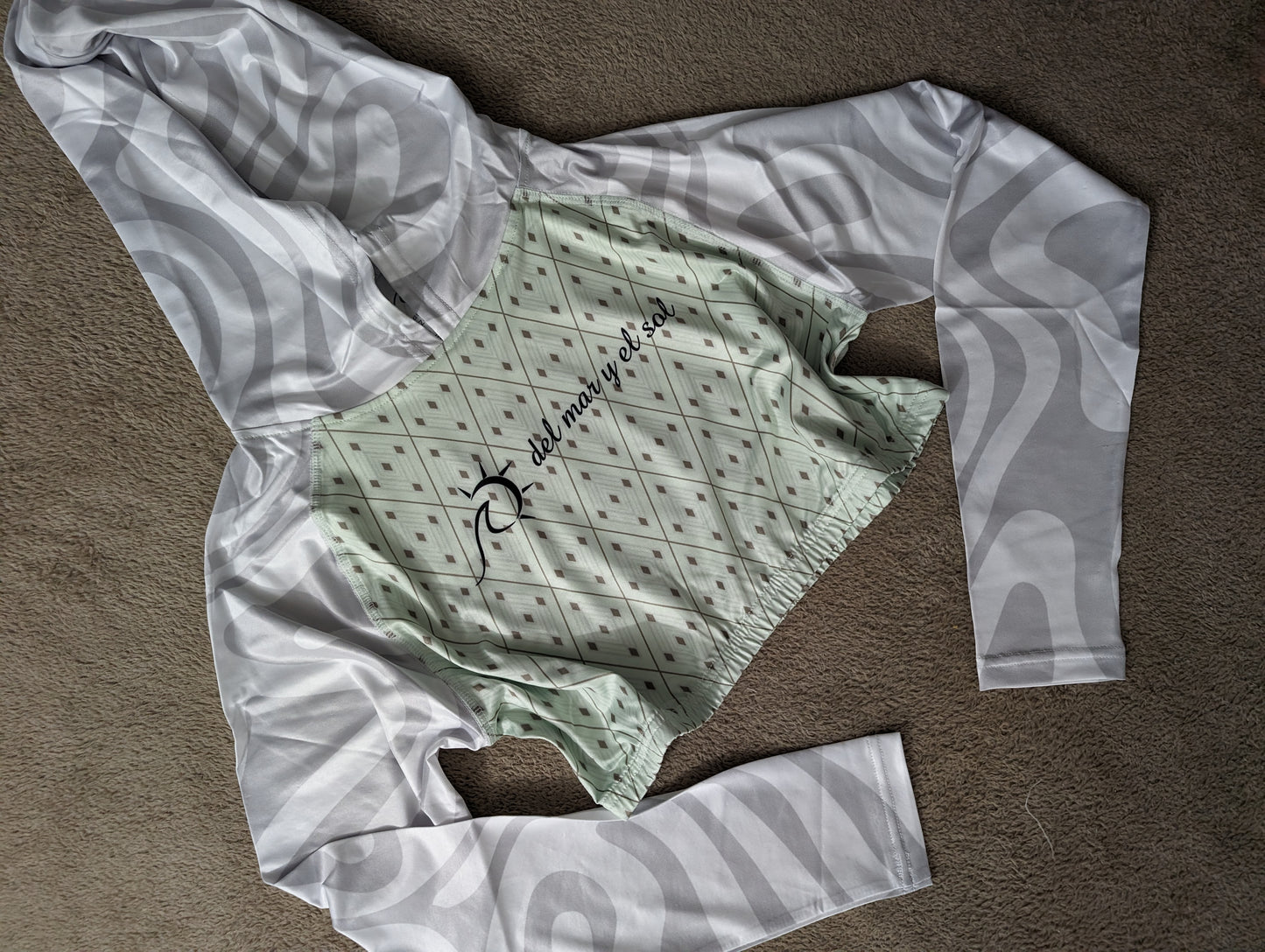 Elegant mint and white cropped rash guard with geometric pattern and white sleeves and hood.