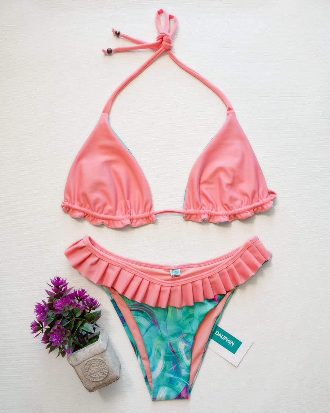 Solid guava pink side of reversible Reef bikini top paired with Coro II aqua and pink patterned bottoms.