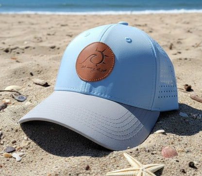 Light blue cap with brown leather patch on a sandy beach