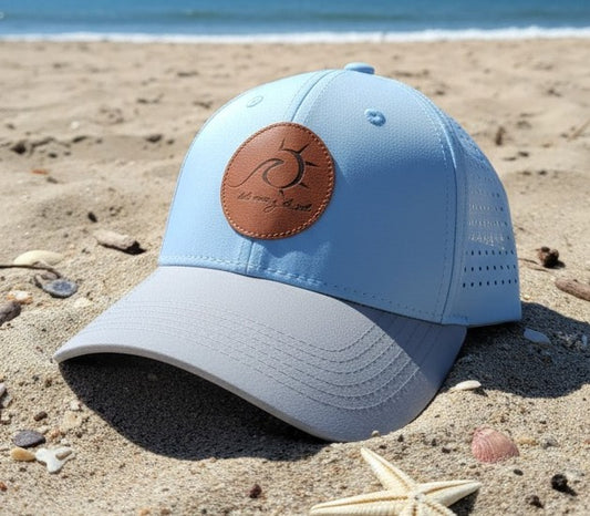 Light blue cap with brown leather patch on a sandy beach
