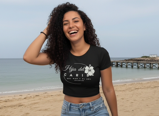 Woman wearing a black t-shirt with text that reads Hija del Caribe Del Mar y el Sol Collection with an hibiscus flower.
