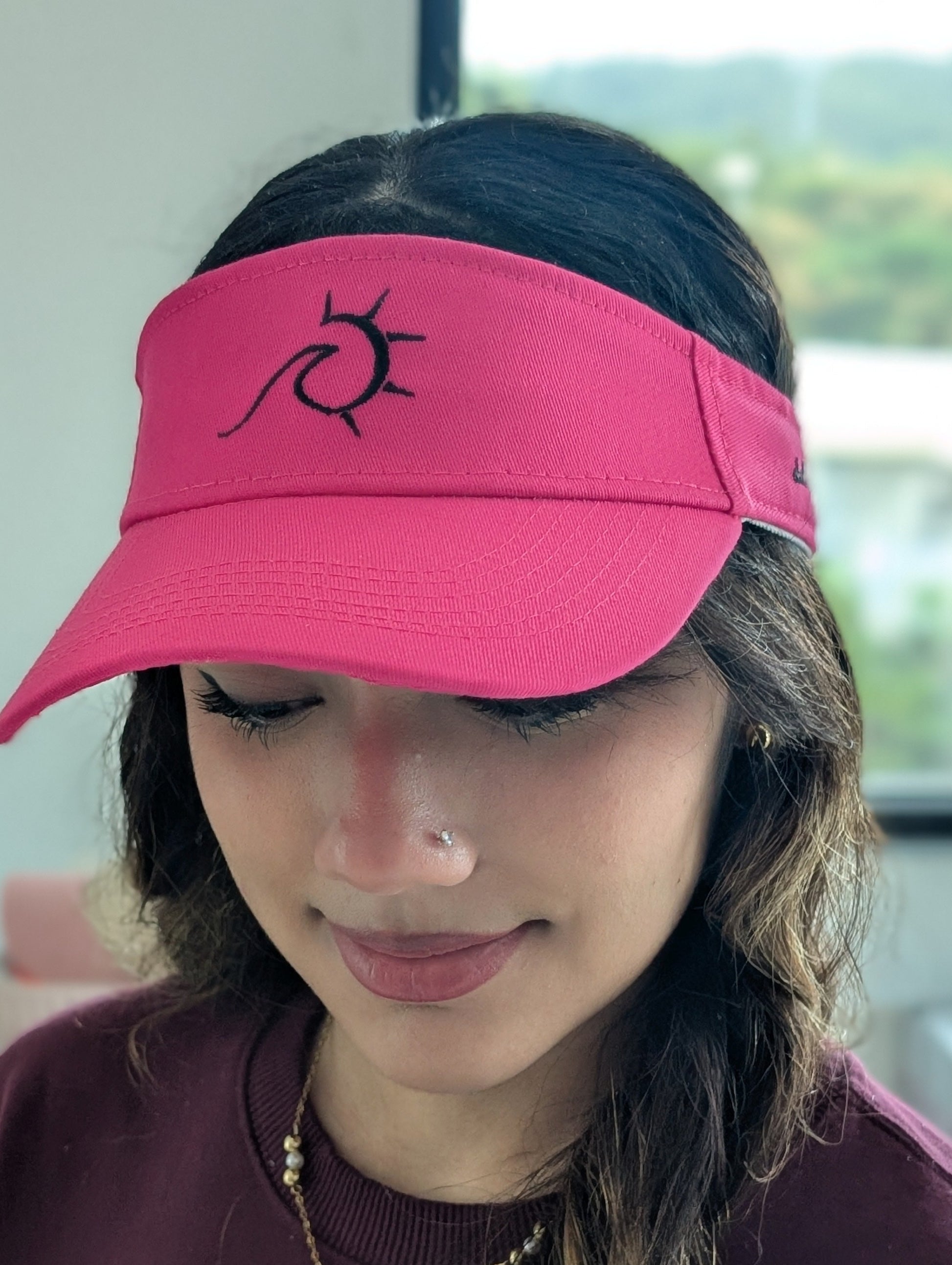 Person wearing a pink visor with a logo of a Wave and Sun