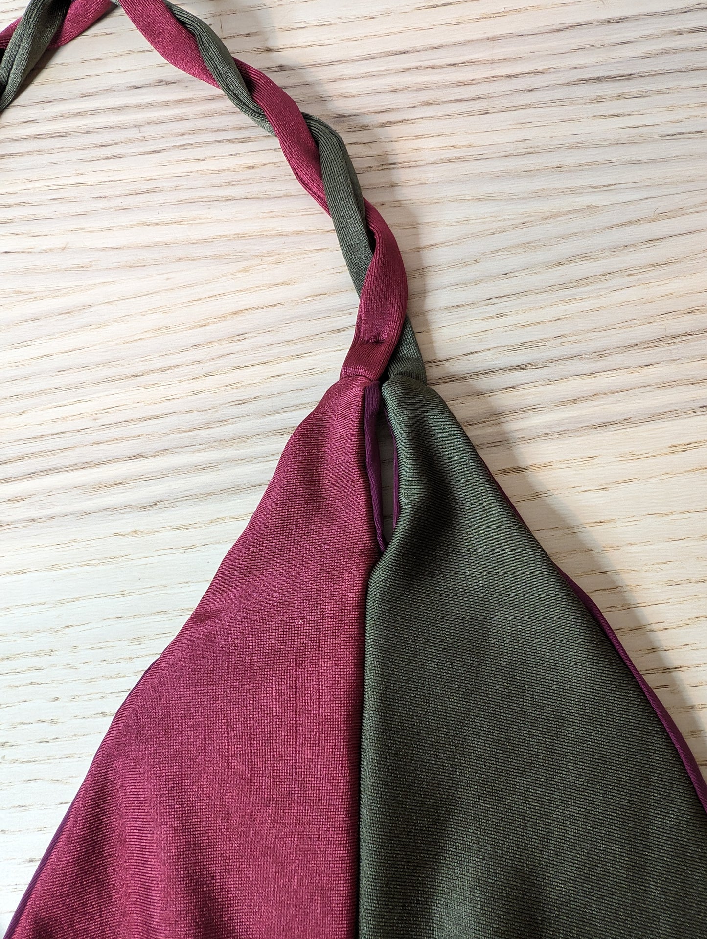 Close-up of the maroon bikini top’s braided neck tie against a wooden backdrop