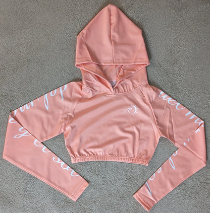 Peach cropped rash guard with white script accents on the sleeves.