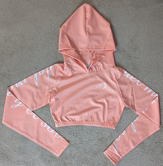 Peach cropped rash guard with white script accents on the sleeves.