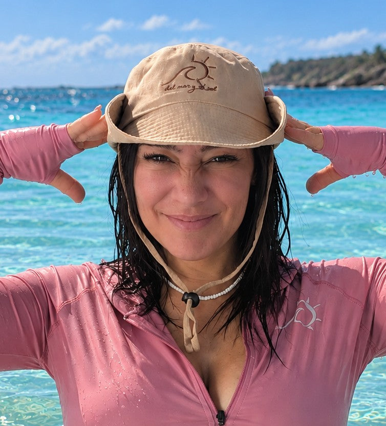 Woman wearing the Marina convertible bucket hat in Sand Beige at the beach with the brim snapped up.