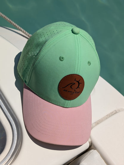 Island Mint and Beige dry fit cap resting on a boat by the sea. 
