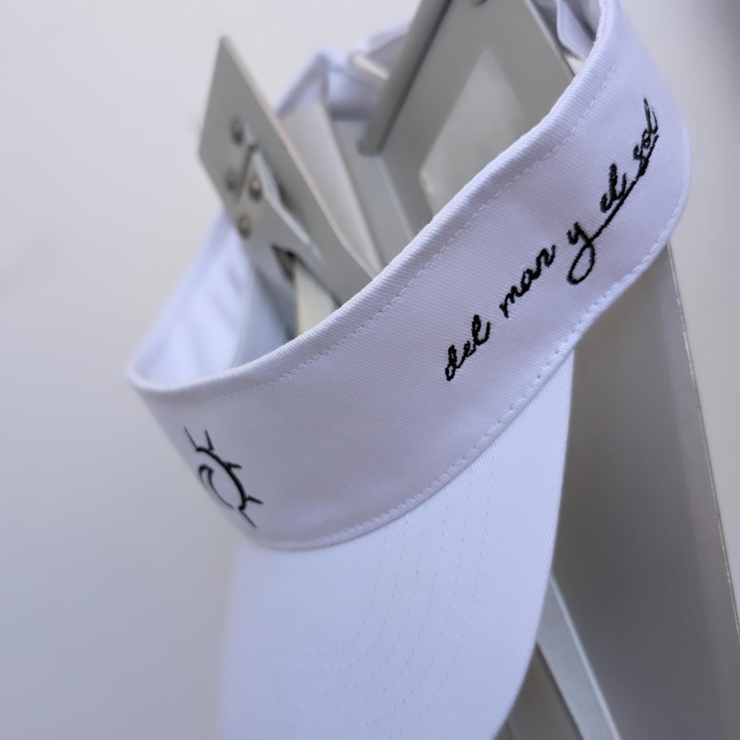 A white visor hat with black text and embroidery, featuring an adjustable velcro strap.